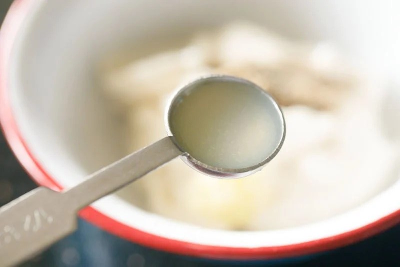 Fresh lemon juice being added to mayo in bowl.