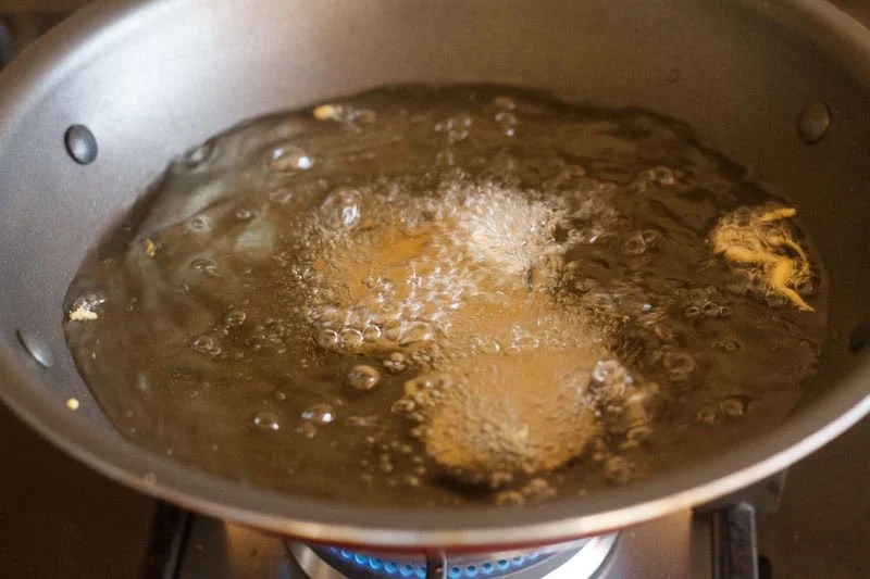 Batter coated potato slices in hot oil.