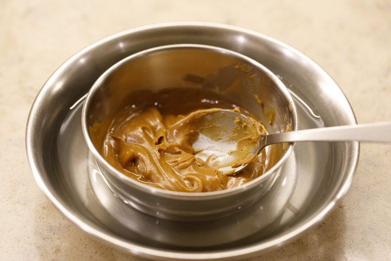 Biscoff spread in a small bowl placed on top of a plate filled with hot water.