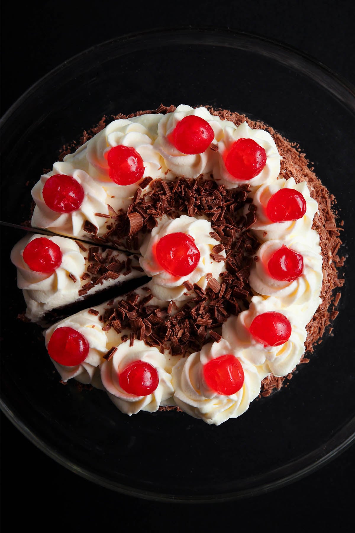 overhead shot of black forest cake on a black plate with a slice being removed
