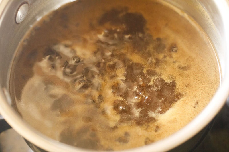 Simmering jaggery syrup in pan.
