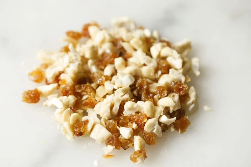 finely chopped cashews and raisins on a white marble board