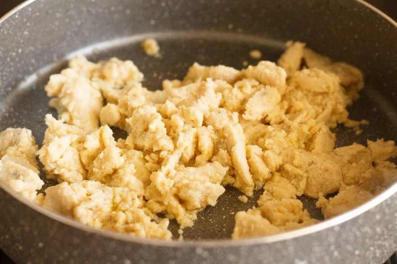 Crumbled mawa in pan being cooked.