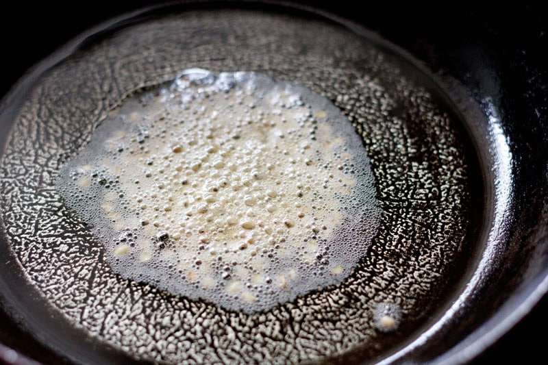 Urad dal added to medium-hot oil in pan.