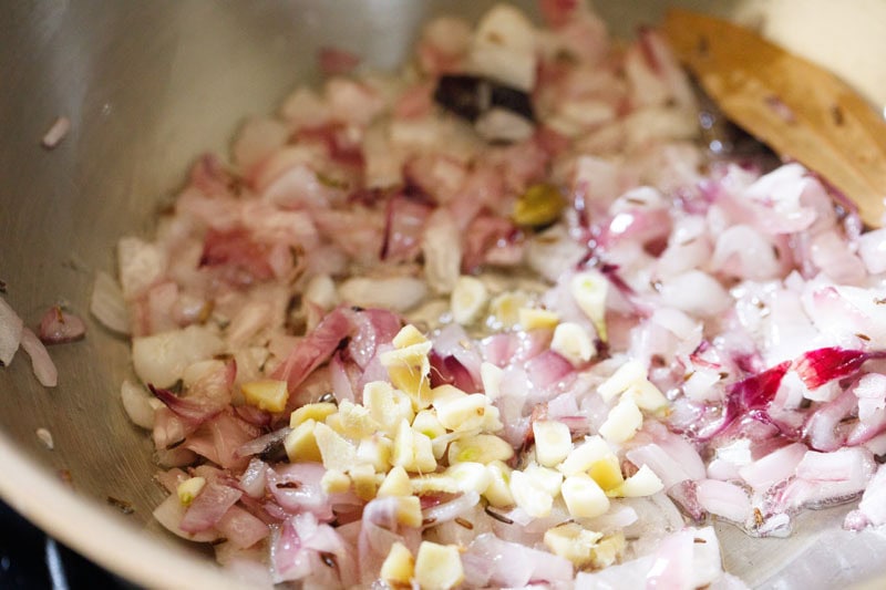 Chopped ginger and garlic over sautéed onions in pan.