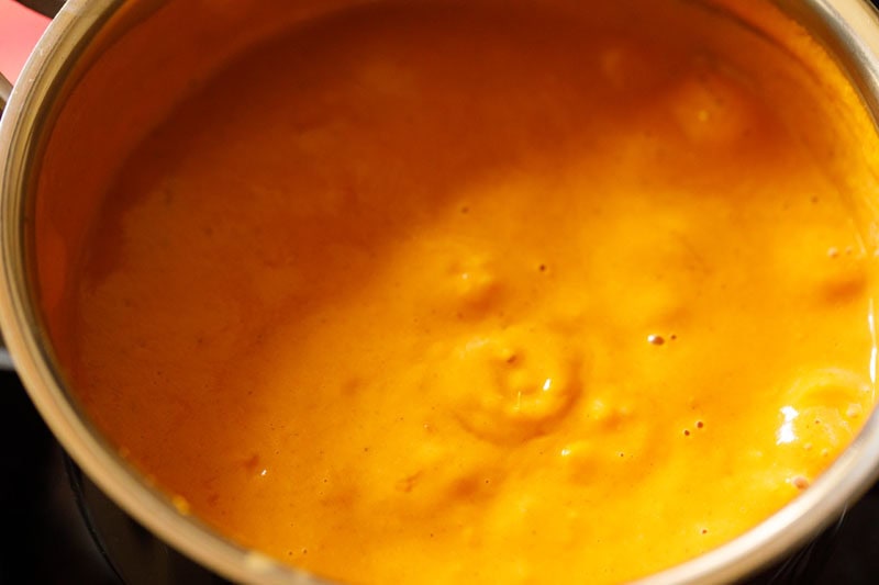 Simmering orange gravy in pan.