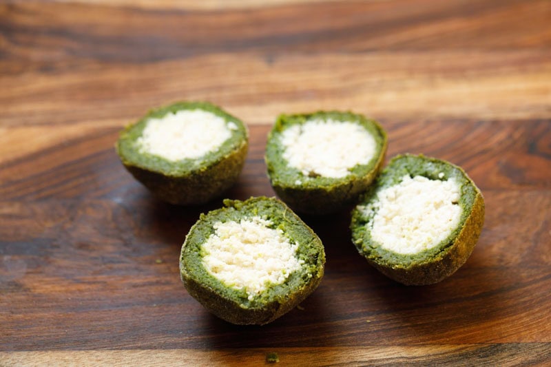Palak kofta halved into two equal pieces.